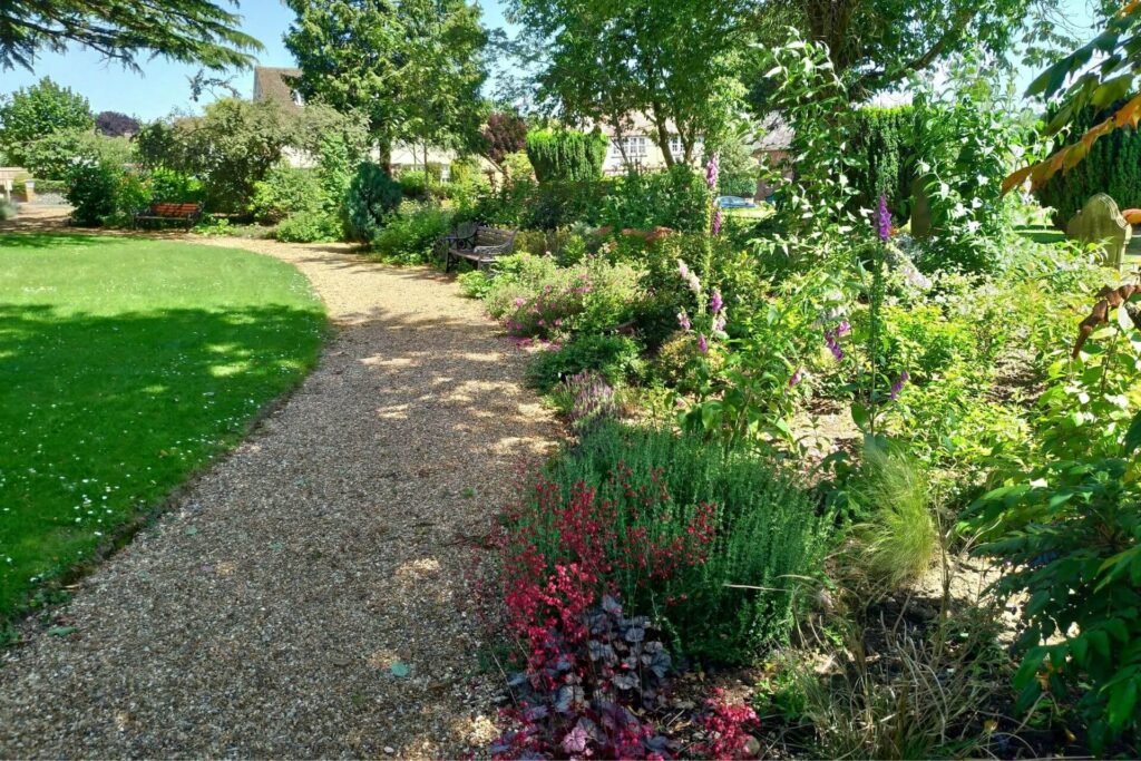 Garden with stone pebbles and wildflowers. Manicured lawn on the left.